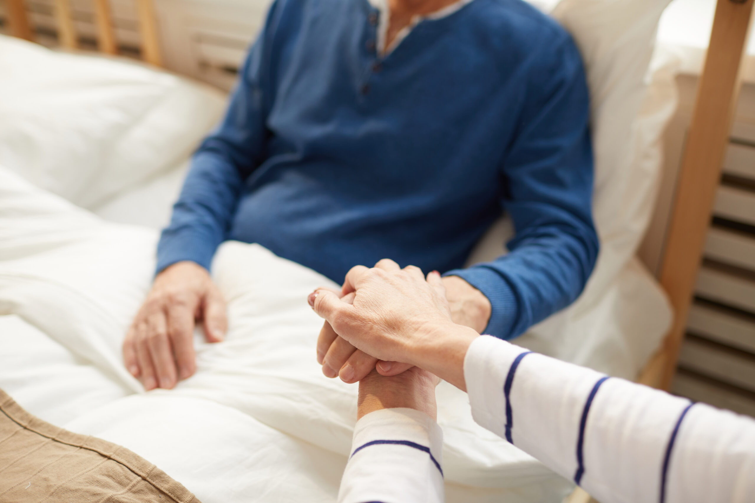 Closeup of senior couple holding hands supporting each other through sickness, copy space